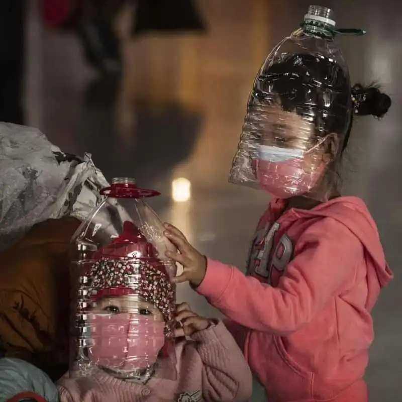 MASCHERINA E BOTTIGLIA DI PLASTICA IN TESTA PER DIFENDERSI DAL CORONAVIRUS