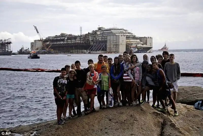 turisti davanti la carcassa della costa concordia