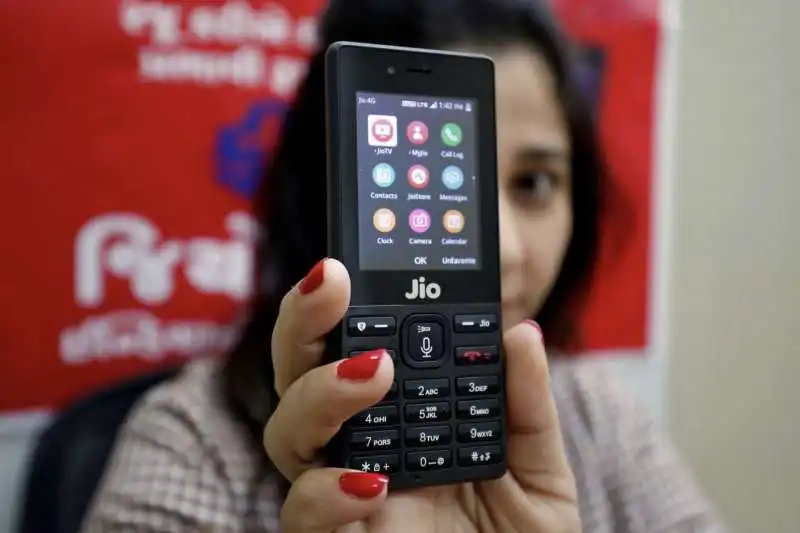 una ragazza fa vedere il suo jiophone nella periferia di ahmedabad, india