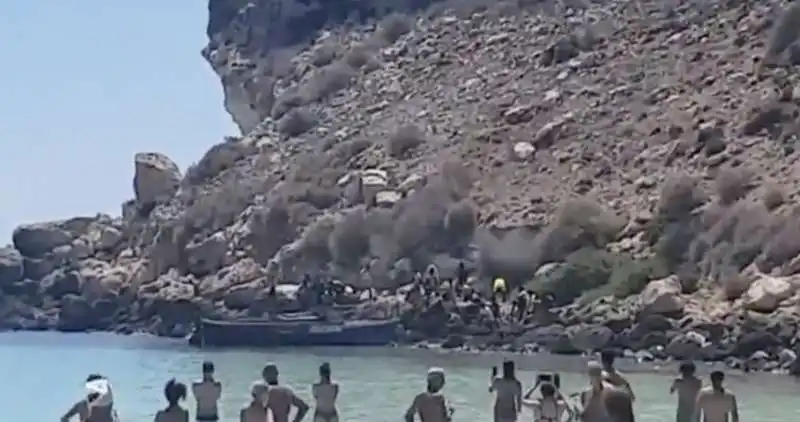 migranti sbarcano sull'isola dei conigli a lampedusa in mezzo ai turisti 1