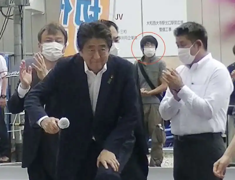 shinzo abe con il suo attentatore alle spalle 