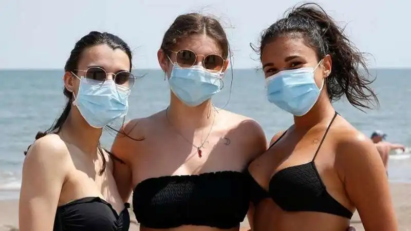 tre ragazze in spiaggia con la mascherina 