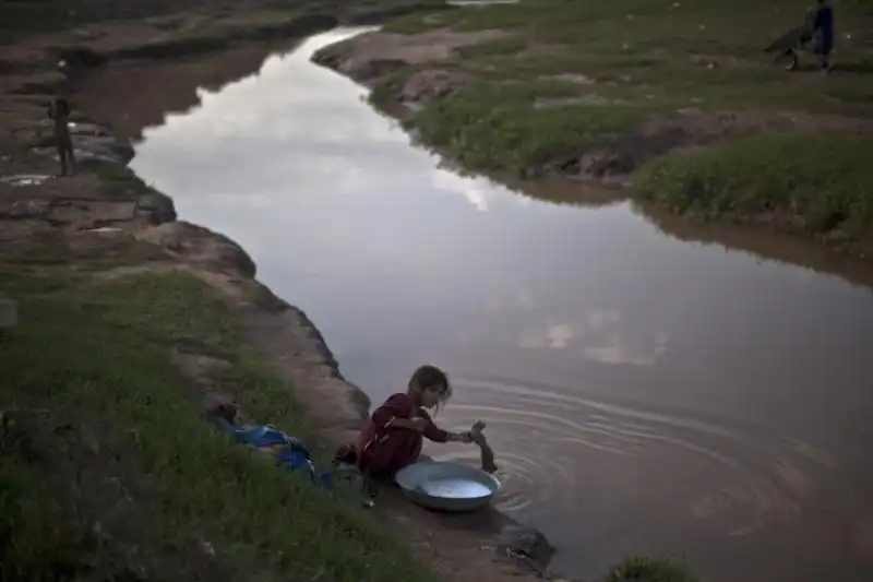 BAMBINA RIFUGIATA AFGHANA LAVA I PANNI NEL FIUME A ISLAMABAD 