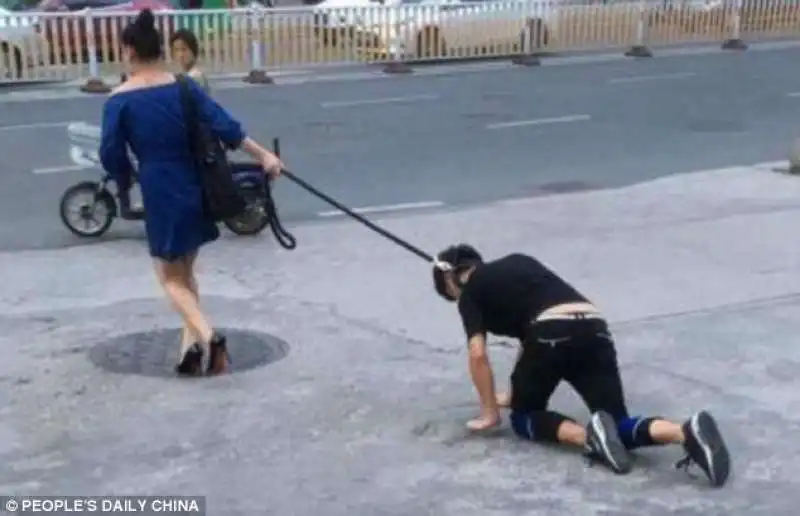 IN CINA UNA DONNA PORTA UN UOMO AL GUINZAGLIO