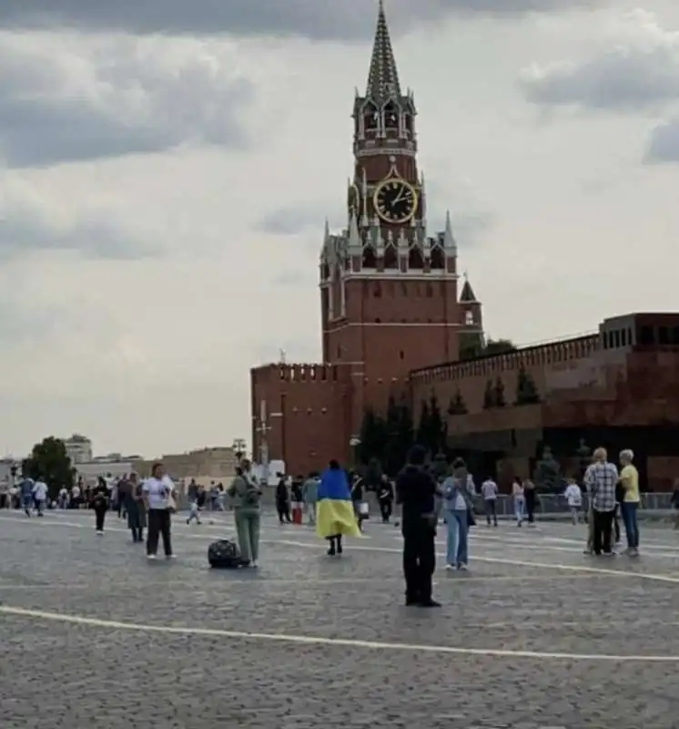 UNA DONNA SFILA SULLA PIAZZA ROSSA A MOSCA CON UNA BANDIERA UCRAINA