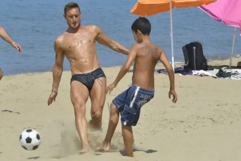 totti gioca a calcio sulla spiaggia