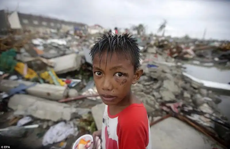 Bambino di 11 anni sopravvissuto al tifone delle Filippine a caccia di cibo e materiale riutilizzabile tra le case distrutte nella città di Tacloban 