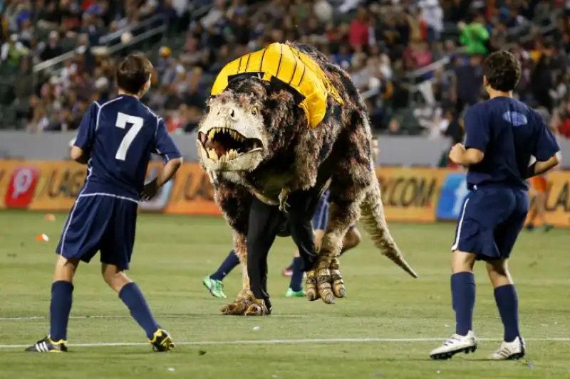 UN UOMO VESTITO DA TIRANNOSAURO REX IN CAMPO DURANTE UNA PARTITA DI SOCCER AMERICAN 