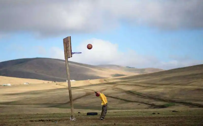 mongolia un ragazzino gioca a basket dopo essersi preso cura dei cavalli