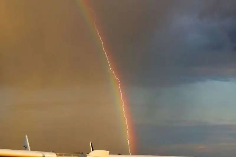 un fulmine colpisce un aereo dentro un arcobaleno