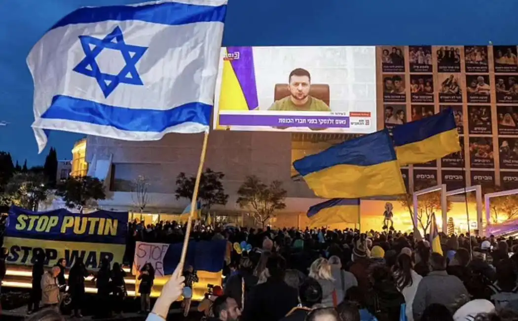 persone in piazza ascoltano zelensky alla knesset. 