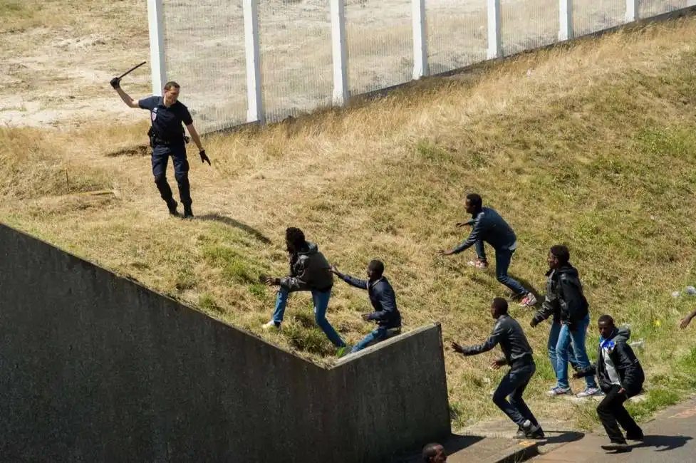 calais un poliziotto allontana gli immigrati dal confine foto philippe huguen