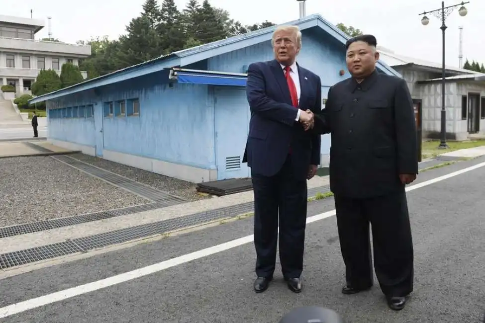 stretta di mano tra donald trump e kim jong un al confine tra le due coree